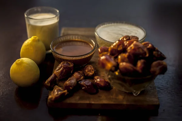 Dates face mask for winter dry skin in a glass bowl consisting of some dates, milk lemon juice and soak cream. Shot of face mask with entire ingredients and some raw dates also.Horizontal shot.