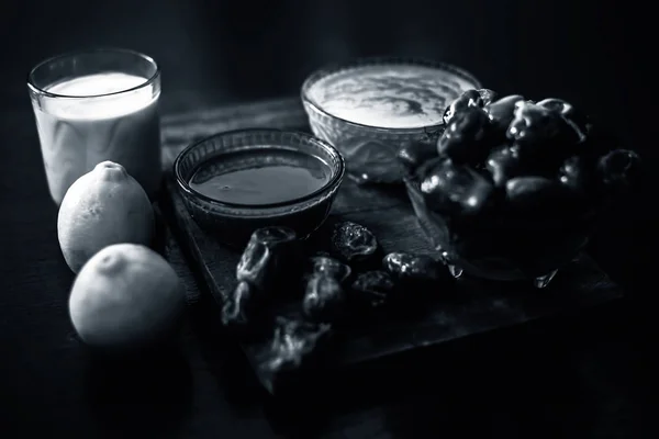 Dates face mask for winter dry skin in a glass bowl consisting of some dates, milk lemon juice and soak cream. Shot of face mask with entire ingredients and some raw dates also.Horizontal shot.