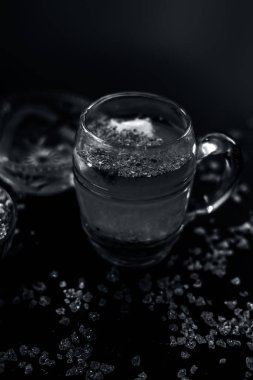 Özel gond katria yaz içeceği, içinde biraz karabiber ve limon suyu olan ahşap bir yüzey üzerinde cam bir bardakta. Yanında da yayılmış gond, sakız, yenilebilir sakız kristalleri..