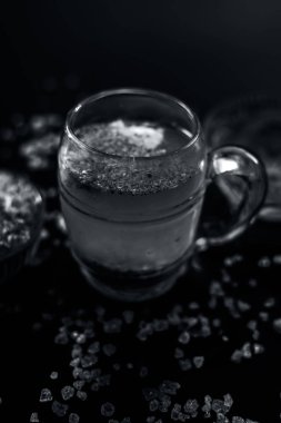 Özel gond katria yaz içeceği, içinde biraz karabiber ve limon suyu olan ahşap bir yüzey üzerinde cam bir bardakta. Yanında da yayılmış gond, sakız, yenilebilir sakız kristalleri..