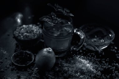 Özel gond katria yaz içeceği, ahşap bir yüzey üzerinde, içinde biraz karabiber ve limon suyu olan cam bardakta. Yanında da biraz yayılmış gond, sakız, yenilebilir sakız kristalleri..