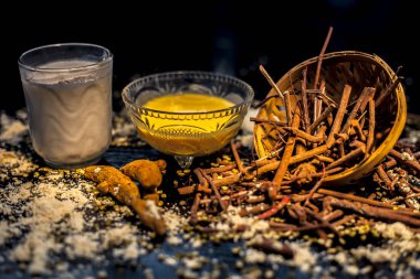 Ayurvedik kan temizleyici ve manjistha, mung fasülyesi, haldi / zerdeçal ve sütten oluşan cilt parlatıcı yüz maskesi. Siyah yüzey üzerinde tüm bileşenleriyle yüz maskesi yatay görüntüsü.