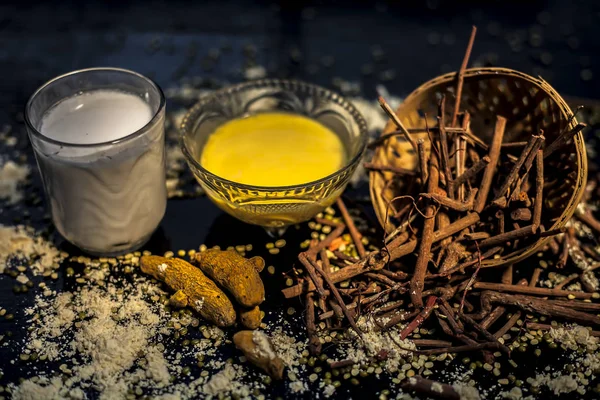 Ayurvedic blood purifier and skin glow face mask consisting of Manjistha, mung bean, haldi/turmeric, and milk. Horizontal shot of face mask with entire constituents with it on a black surface.