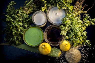 Face mask for acne and blackheads on the black wooden glossy surface consisting of some cilantro leaves, lemon, honey, and some milk. It helps to rejuvenate the skin and clean the affected area.