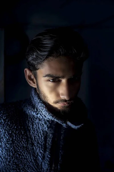 身穿深蓝色羊毛衫的年轻男性胡子模特的肖像照片 在他的脸上用伦勃朗浅色技术在黑色背景下摆姿势拍摄 — 图库照片
