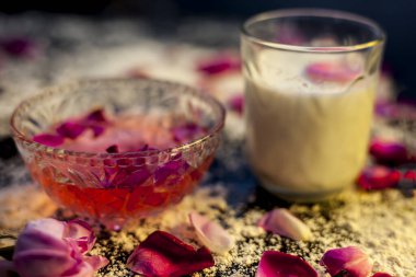 Siyah renkli bir tahtanın üzerindeki yağlı cilt için buğday unu maskesi gül suyu, süt, buğday unu ve yağlı cilt için çiğ bal içerir. Yüzeydeki tüm malzemelerden serpiştirilmiş un..