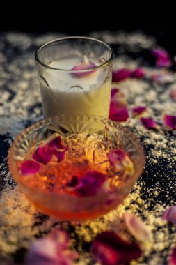 Siyah renkli bir tahtanın üzerindeki yağlı cilt için buğday unu maskesi gül suyu, süt, buğday unu ve yağlı cilt için çiğ bal içerir. Yüzeydeki tüm malzemelerden serpiştirilmiş un..