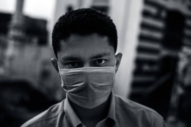 Mavi tişört giyen ve mavi maske takarak kendini koruyan sağlık düşkünü bir şirket çalışanının portresi. Covid 19 koruma ve Coronavirus hastalığını önleme.