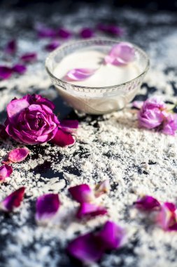 Taze krema ve buğday unundan oluşan bir tahtanın üzerinde cilt beyazlaması için yüz maskesi. Biraz ısı unu ve gül yapraklarıyla bir kase krema. Dikey çekim.