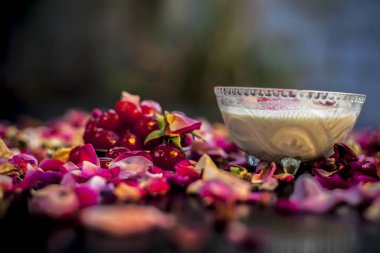 Yoğurtla karıştırılmış kirazlardan oluşan siyah ahşap bir tahtanın üzerindeki deri parlatıcı Diy maskesi. Taze kiraz, yoğurt ve gül yapraklarıyla birlikte..