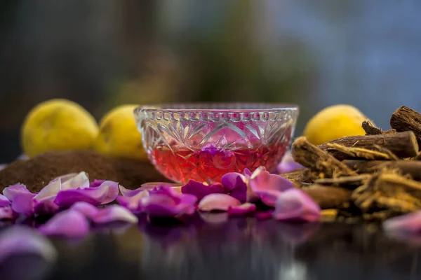 Close up face mask of age-old herb Mulethi for radiant skin on a black surface consisting of some lemon juice, licorice powder, rose water, and some sandalwood powder. Shot of all the ingredients.