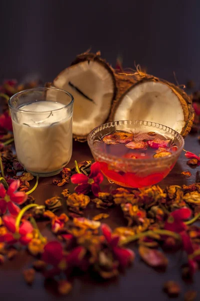 Coconut milk face mask for protection against UV ( Ultraviolet rays) on a brown colored surface consisting of some rose water and coconut milk. Shot of all the ingredients on the surface.;