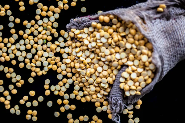 Close up shot of raw chickpea lentil/Yellow lentil in a gunny bag on a black shiny surface