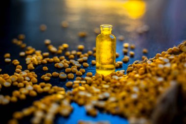 Küçük bir cam şişede nohut özü ve ahşap bir yüzey üzerinde çiğ sarı mercimek..