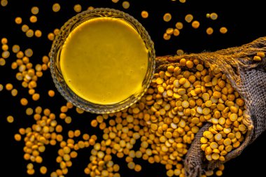 Siyah yüzeyde cam bir kasede taze haşlanmış nohut ezmesi ve çiğ nohut mercimeği..