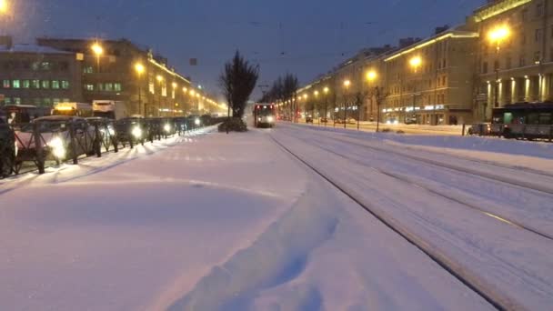Die Straßenbahn nähert sich auf schneebedeckten Schienen der Bushaltestelle. russland, saint-petersburg, 8. november 2016 — Stockvideo