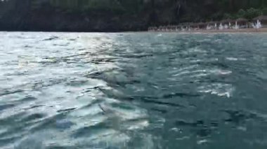 Deniz suyunun yüzeyinden çekim yapmak, dalgalar, dalgalar, deniz gücü, sazdan çatılı şemsiyeli plaj, ufukta dağ