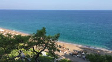 yükseklikten deniz manzarası, turkuaz deniz suyu, ışık dalgası, geniş kumlu sahil, plajın önündeki yüksek çam ağaçları, yaz, tatil