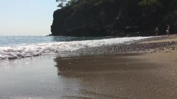 沙滩上 水在沙滩上流过 又返回 部分被沙子所吸收 海滩关闭了岩石海岸 — 图库视频影像