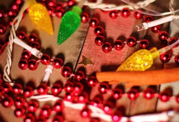 Noel kompozisyonu, ipte bir sürü kırmızı top, tarçın çubukları, yanıp sönen elektrik çelengi, farklı renkler ve şekiller, Noel, mutlu yıllar.