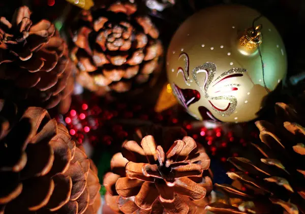 Yeni yıl kompozisyonu, çeşitli koniler, altın top, dekorasyon, kırmızı ışıklar, aydınlık karanlık, tatil atmosferi