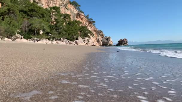 美丽的沙滩 靠近悬崖 在沙滩上飘扬着白色的泡沫 暑假的好地方 阳光灿烂 — 图库视频影像
