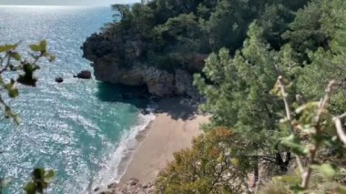 Dağların, kayaların, kumların, deniz dalgalarının arasında harika bir kumsalın yüksekliğinden manzara sürekli sahile gelen rüzgar ağaçları sallıyor, çoğunlukla çam ağaçları, doğayı izlerken bir an rahatlama, denizin sesi, karantinadaki anılar.