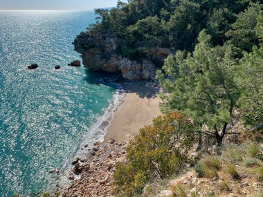 Dağların, kayaların, kumların, deniz dalgalarının arasında harika bir kumsalın yüksekliğinden manzara sürekli sahile gelen rüzgar ağaçları sallıyor, çoğunlukla çam ağaçları, doğayı izlerken bir an rahatlama, denizin sesi, karantinadaki anılar.