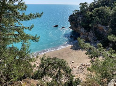 Dağların, kayaların, kumların, deniz dalgalarının arasında harika bir kumsalın yüksekliğinden manzara sürekli sahile gelen rüzgar ağaçları sallıyor, çoğunlukla çam ağaçları, doğayı izlerken bir an rahatlama, denizin sesi, karantinadaki anılar.