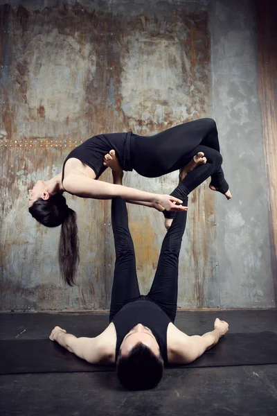 Young athletic couple practicing acroyoga.
