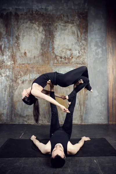 Young athletic couple practicing acroyoga.