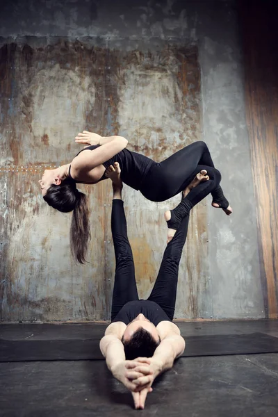 Young athletic couple practicing acroyoga.