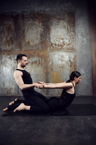 Young athletic couple practicing acroyoga.