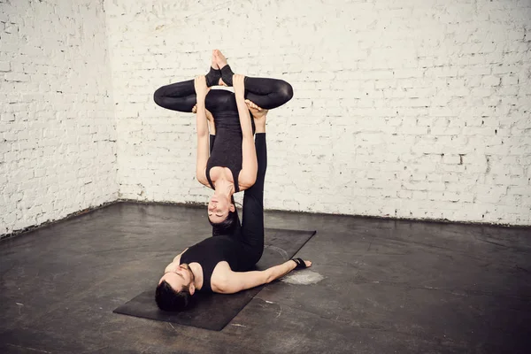 Young athletic couple practicing acroyoga.