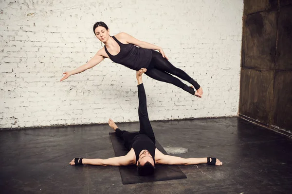 Young athletic couple practicing acroyoga.