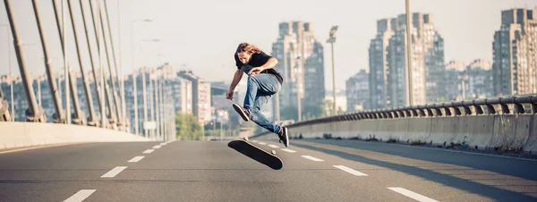 Skater haciendo trucos y saltando en el puente de la carretera de la calle —  Fotos de Stock