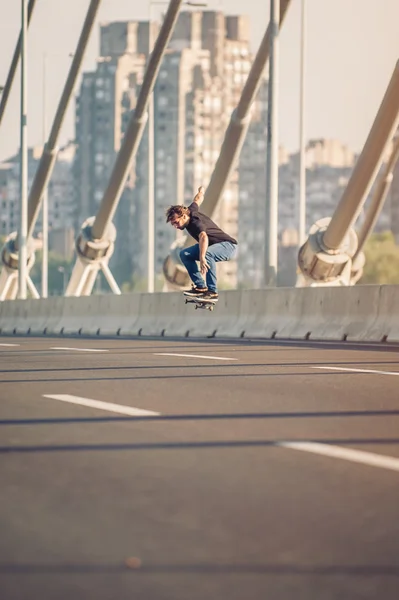 Skater robi triki i skoki na ulicy mostem. Fr — Zdjęcie stockowe