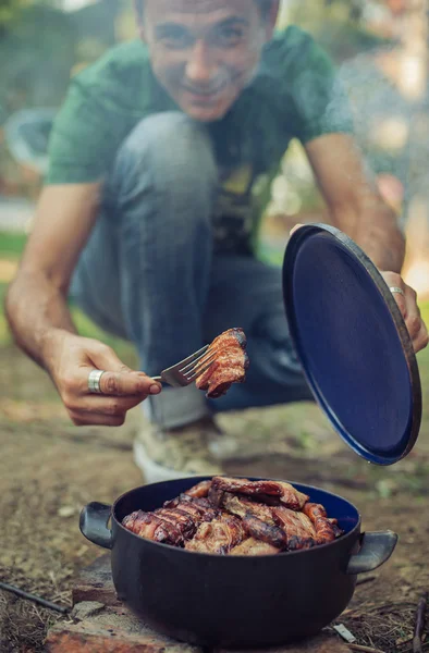 Mann grillt und legt gebratenes Fleisch in den Topf — Stockfoto