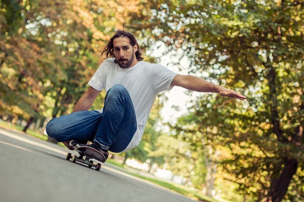 Скейтбордист приседает на скейте и катается по лесу — стоковое фото
