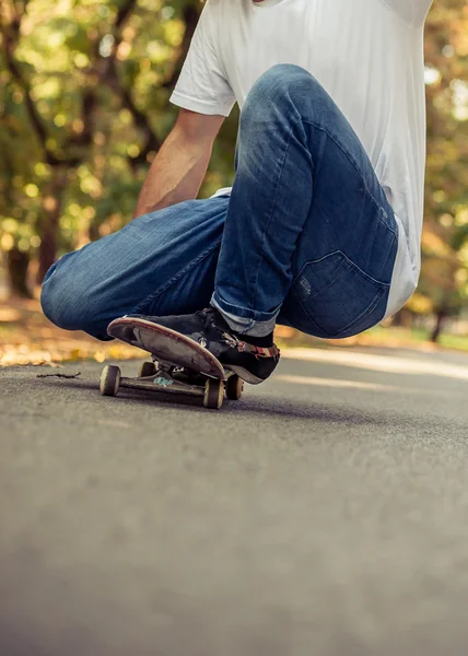 Skateboarder gehurkt op een skate en rijden door het bos — Stockfoto