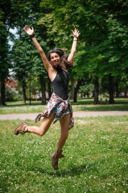 Eğleniyor ve güneşli bir günde ormanda atlama genç kadın