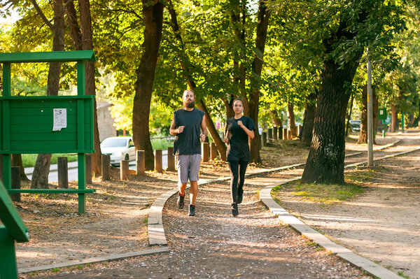 Young couple running on the jogging track through the forest