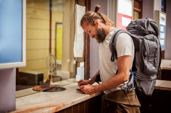 Мужчина-турист покупает билет на вокзале — стоковое фото
