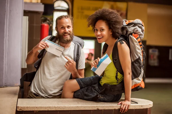 Happy and euphoric couple of backpacker tourists show tickets fo