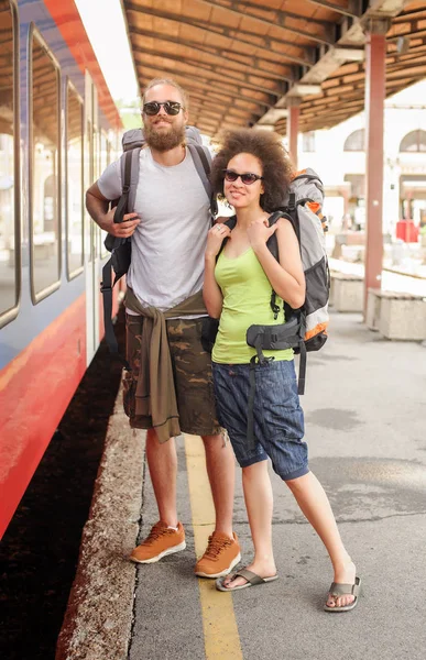 Ett par backpacker turister väntar på att ombord på ett tåg — Stockfoto