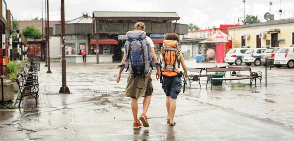 两名游客背着背包走在雨中 — 图库照片