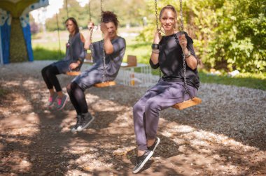 Üç kız arkadaş salıncağa sallanan