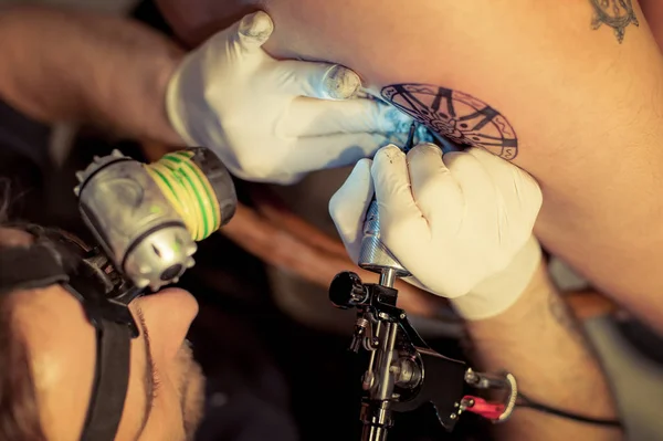 Mestre feminino faz tatuagem nas costas para cliente masculino no