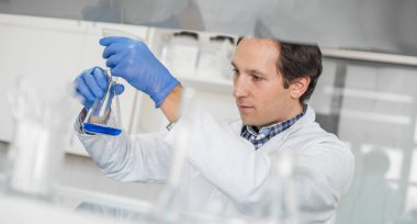 Erkek laboratuvar araştırmacı mavi sıvı ile sınamalarını gerçekleştirir