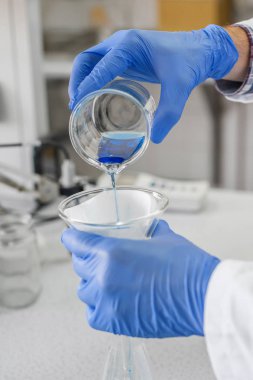 Testler ve dökme mavi sıvıyı laboratuvar teknisyeni gerçekleştirir